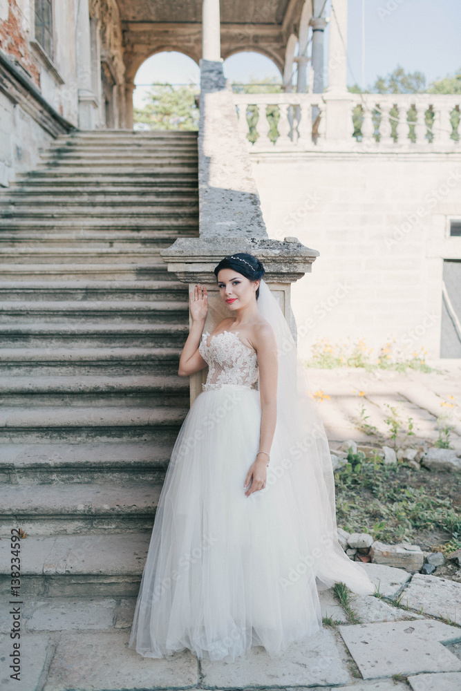 beautiful and young bride in white dress standing near stairs beautiful and young bride in white dress standing near stairs