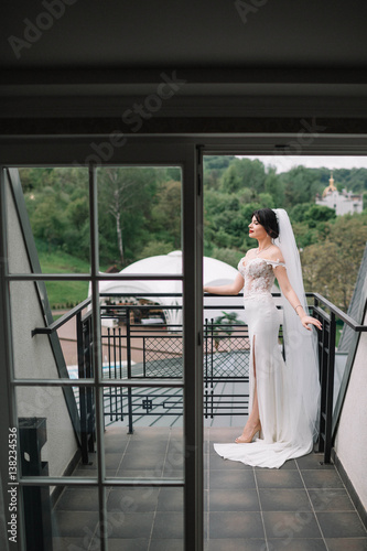 beautiful and young bride in white dress standing on the balcony photo