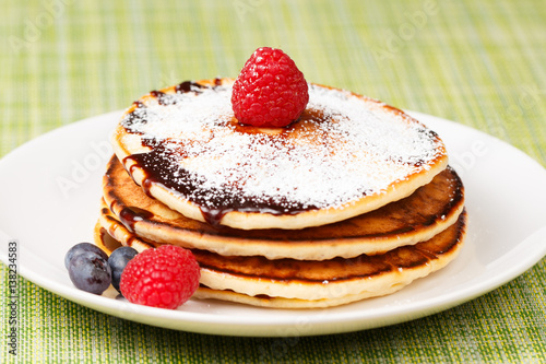 Pile of Pancakes with blueberries and raspberries, chocolate sauce and powder sugar