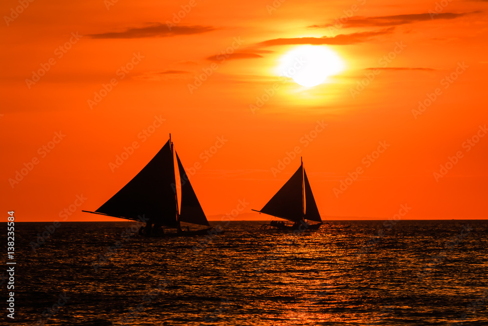 Sailing boats at sunset on a tropical ocean