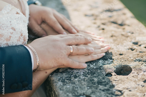 hands of the groom with wedding ring holding hands of bride