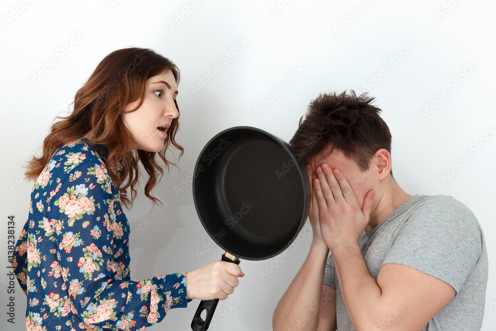 Pretty woman with frying pan scolding guilty man Pretty woman with frying pan scolding guilty man
