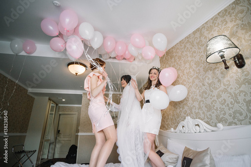 beautiful and young bride in veil with bridesmaids having fun