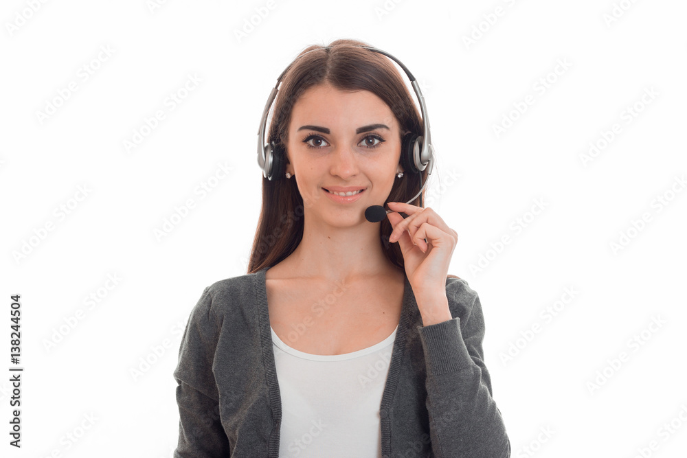 Charming brunette woman working in call center with headphones and microphone smiling on camera isolated on white background Charming brunette woman working in call center with headphones and microphone smiling on camera isolated on white background