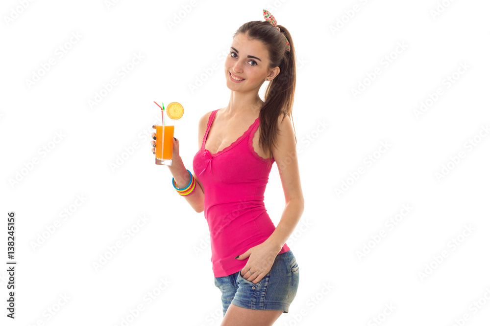 Cheerful young brunette woman in pink shirt drinks fresh orange cocktail and smiling on camera isolated on white background Cheerful young brunette woman in pink shirt drinks fresh orange cocktail and smiling on camera isolated on white background