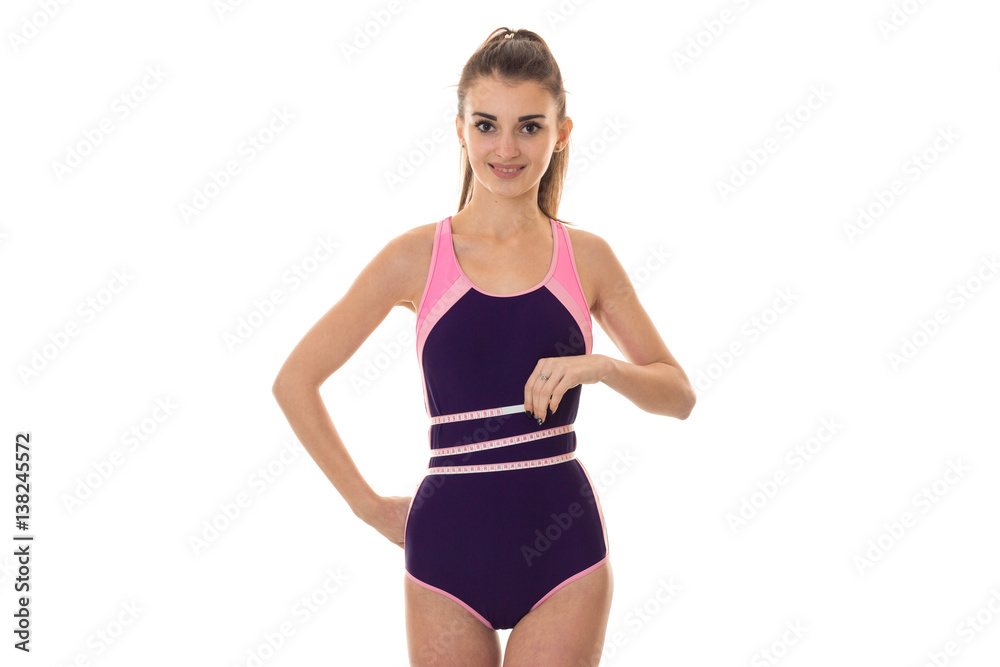 Cheerful young sexy brunette sports woman in body swimsuit smiling on camera and measure her waist isolated on white background Cheerful young sexy brunette sports woman in body swimsuit smiling on camera and measure her waist isolated on white background