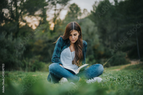 Chica leyendo un libro en el bosque photo