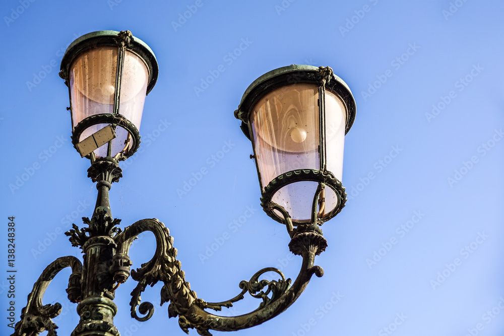 Classic old lamp post isolated on a blue sky background close up