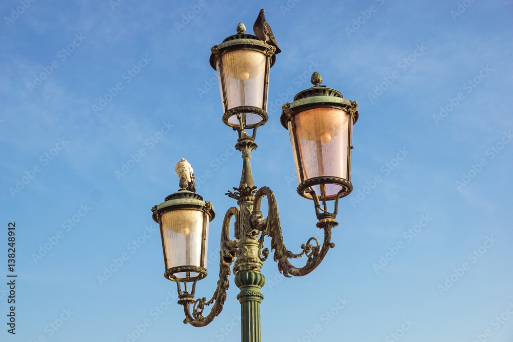 Classic old lamp post isolated on a blue sky background close up