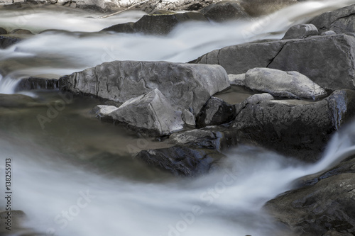 Rocks in stream with smooth flowing water. © Arkadiusz Fajer
