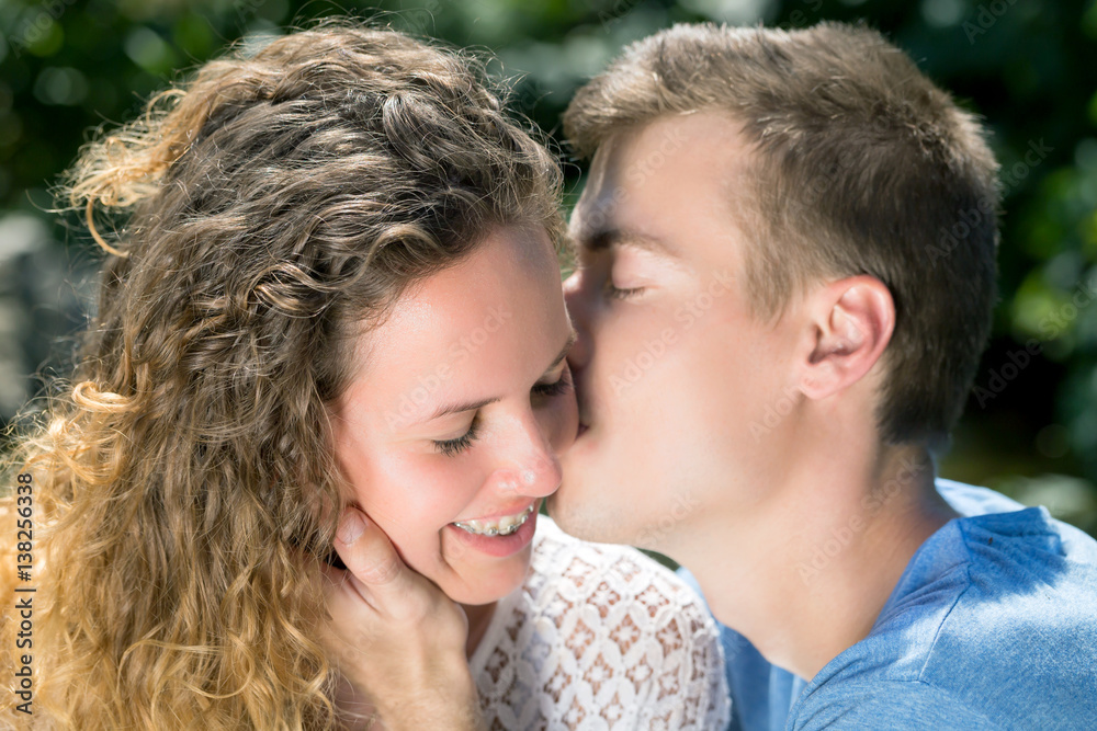 Foto de young couple kiss, boyfriend kissing girlfriend face in a