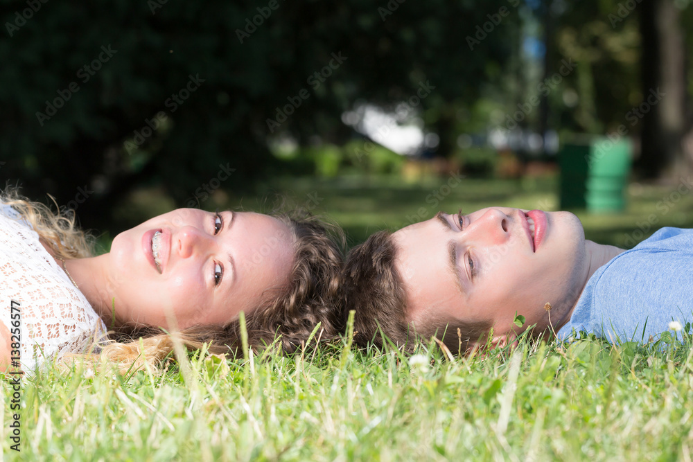 young couple lying in a grass head to head in a park in summer young couple lying in a grass head to head in a park in summer