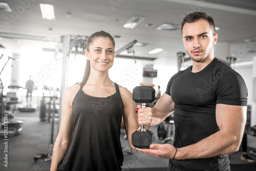 Woman doing bicep curls in gym with her personal trainer