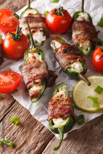 jalapeno peppers wrapped in bacon and stuffed with cream cheese close-up. vertical