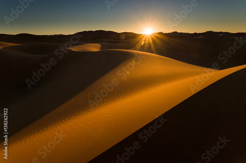 Sunrises just above the horizon at the Dunes of Hassi Labiad, Sahara, Morocco