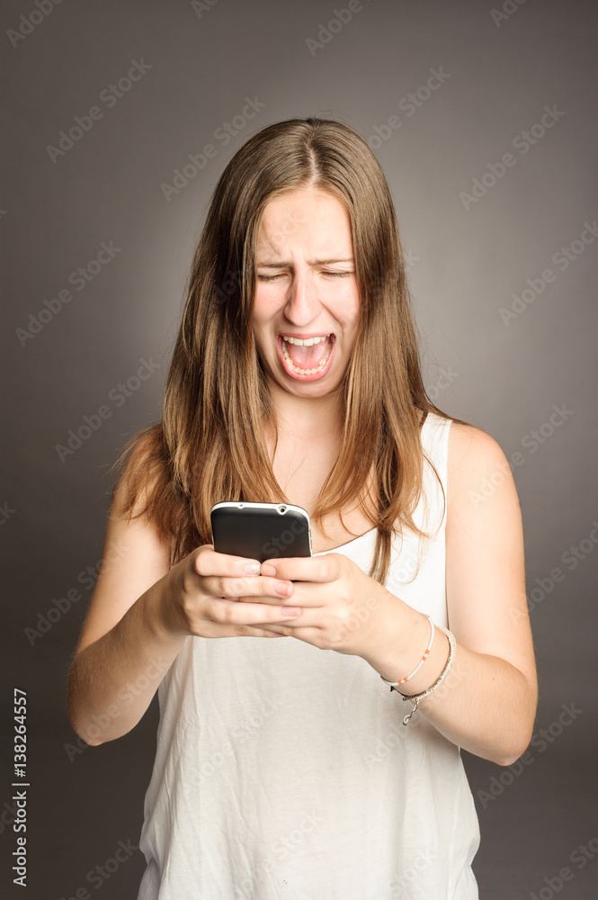 young woman holding two cellulars on a gray background young woman holding two cellulars on a gray background