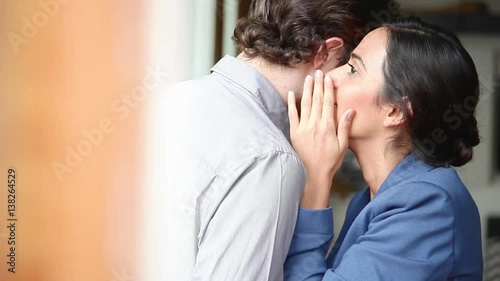 Woman whispering into man's ear