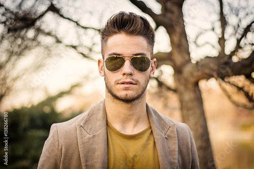 Handsome young man walking along rural road, looking confident and relaxed