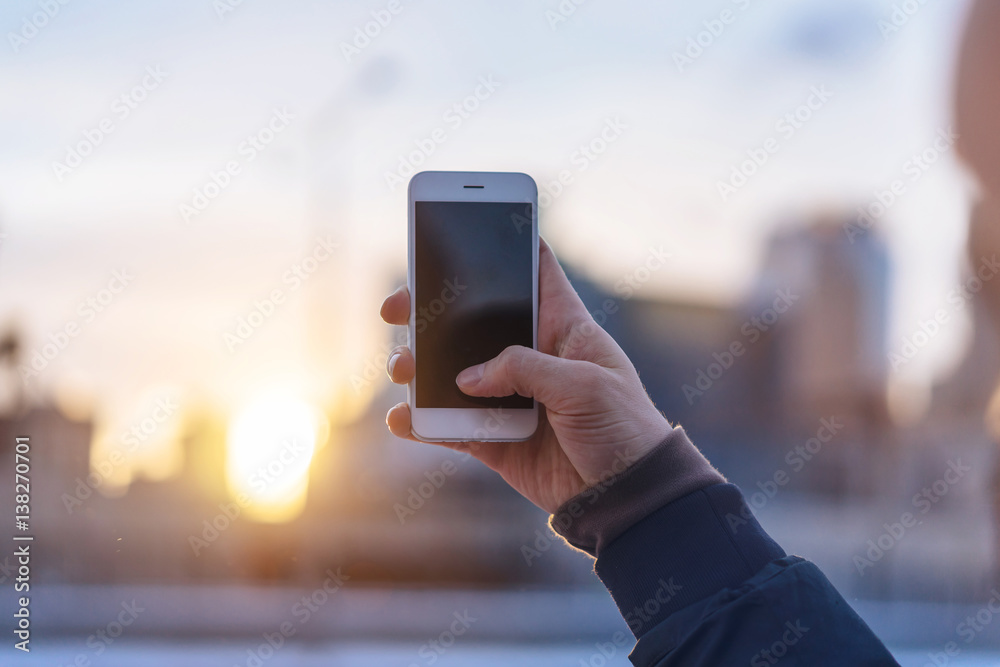 Close-up of male hand holding and using smart phone with city line on the background, Man taking photos the City, blurred background, shallow DOF