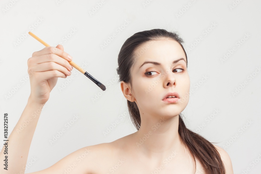 dark-haired woman looking at make-up brush dark-haired woman looking at make-up brush