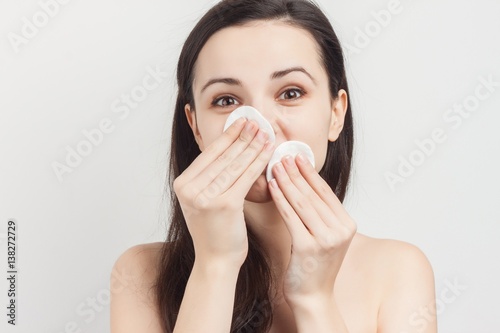 woman wiping her face with cotton pads