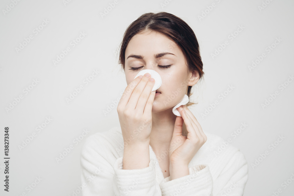woman wiping her face with a cotton pad woman wiping her face with a cotton pad