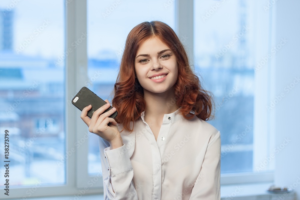 woman with a phone in her hand smiles at the camera