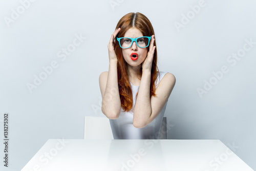 woman in blue glasses is sitting at the table