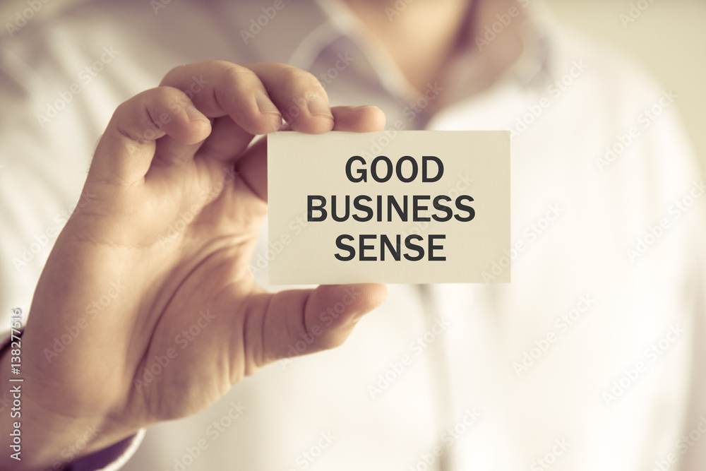 Businessman holding GOOD BUSINESS SENSE message card