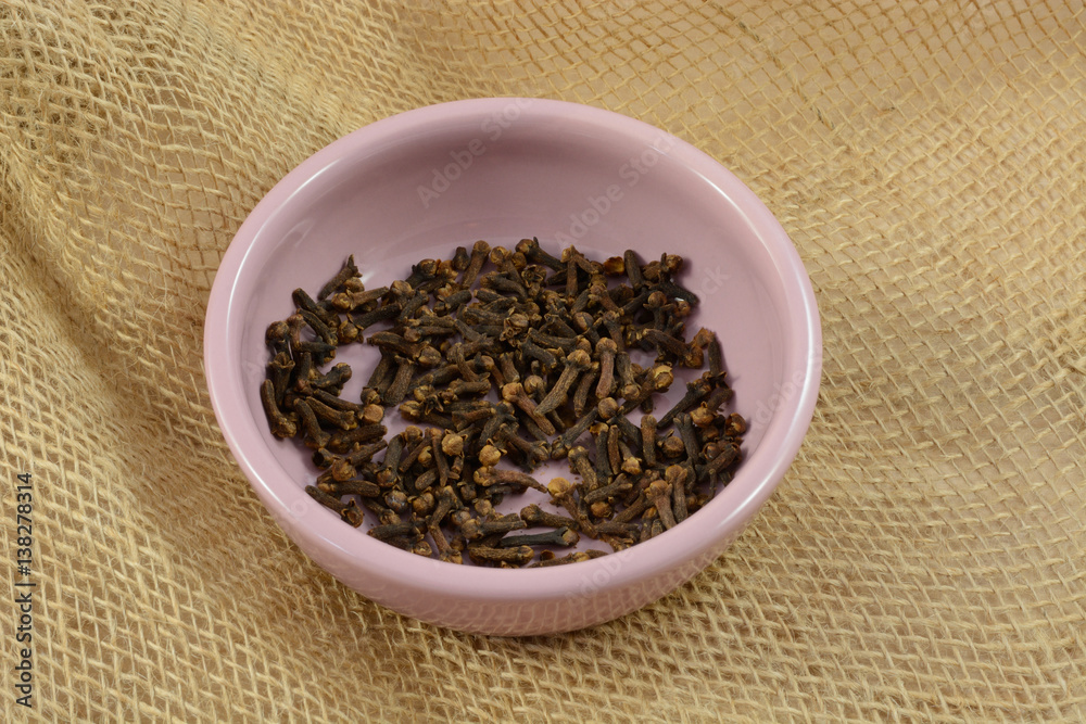 Whole cloves spice in pink dish on burlap Whole cloves spice in pink dish on burlap