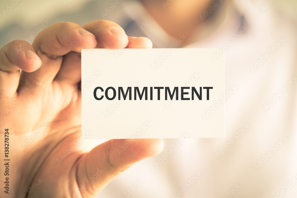 Businessman holding COMMITMENT message card Businessman holding COMMITMENT message card