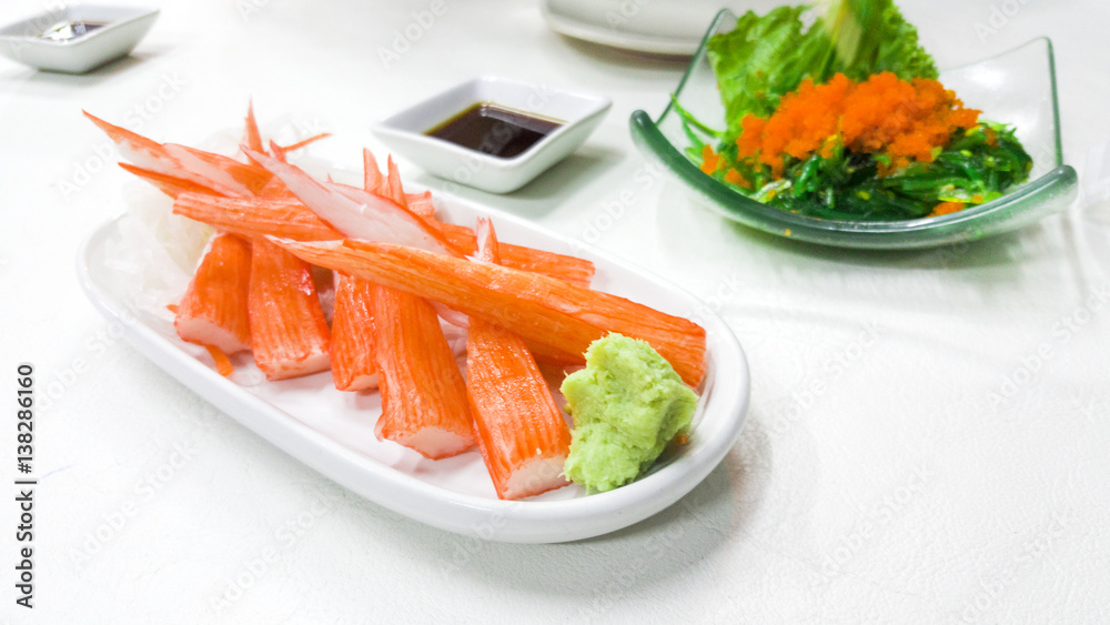 Crab sticks and wasabi in white saucer on table Crab sticks and wasabi in white saucer on table