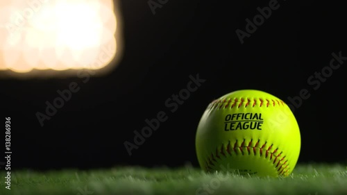 A softball spins under the stadium lights. photo