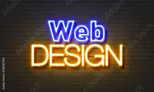 Web design neon sign on brick wall background.