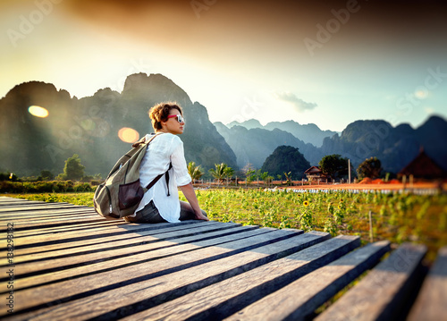 Happy tourist woman meets a sunset overlooking the mountains and fields. Travelling in Asia