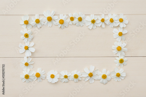Rectangle white flower frame of Spanish needle on light brown wood from top view