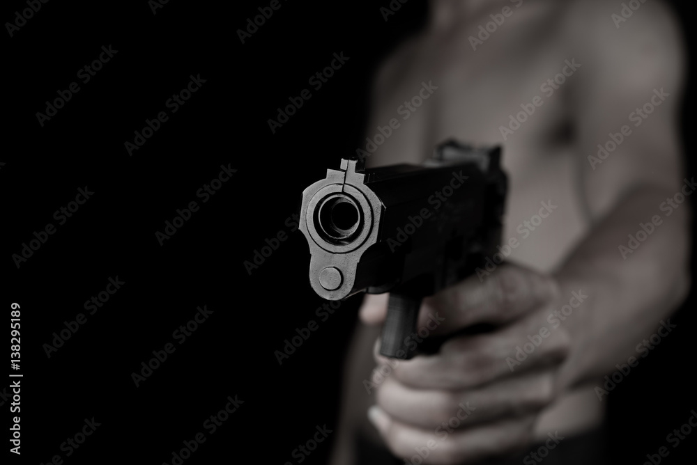 Man holding and shoot gun thief or bandit on dark black background Man holding and shoot gun thief or bandit on dark black background