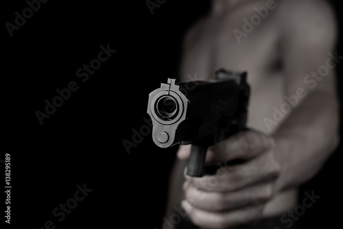 Man holding and shoot gun thief or bandit on dark black background © Love the wind
