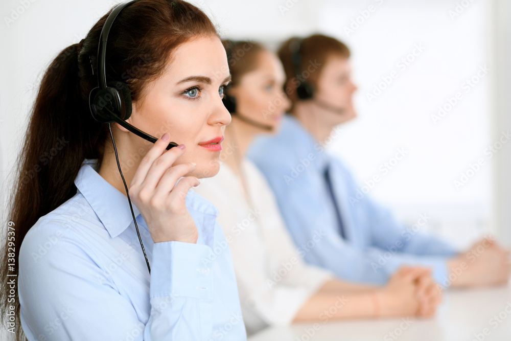 Call center operators. Focus at brunette business woman in headset Call center operators. Focus at brunette business woman in headset