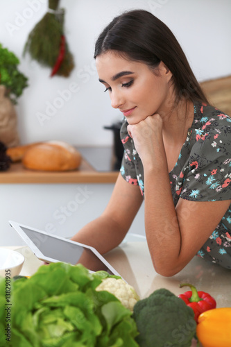 Young hispanic  woman is making online shopping by tablet computer and credit card. Housewife found new recipe for  cooking in a kitchen