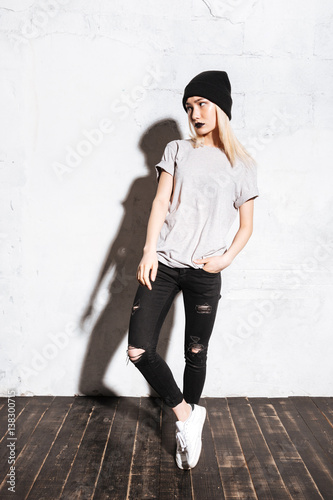 Attractive woman in hat and torn jeans with black lipstick