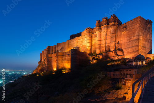 Glowing cityscape at Jodhpur at dusk. The majestic fort perched on top dominating the blue town. Scenic travel destination and famous tourist attraction in Rajasthan, India.