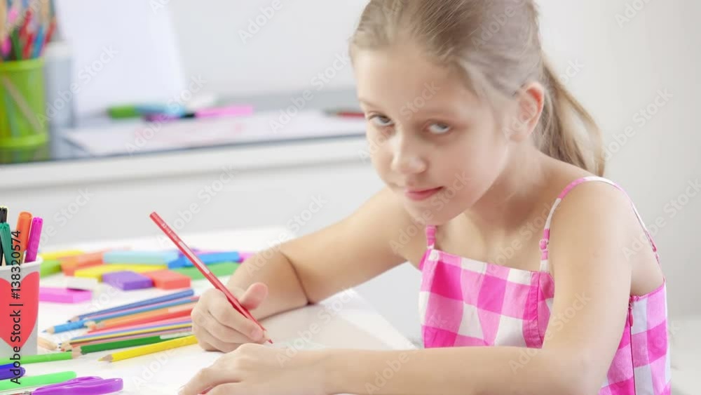 Seven years old girl drawing and coloring on a paper at home. Girl looking at camera and smiling.
Seven years old girl drawing and coloring on a paper at home. Girl looking at camera and smiling.