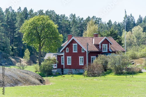 Ett rött hus med vita knutar fotat en vårdag på Värmdö photo