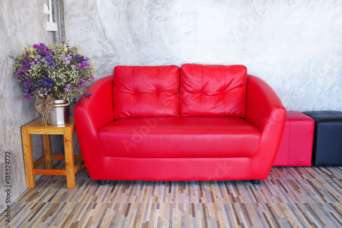 Red sofa in a room with wood tiled floors.