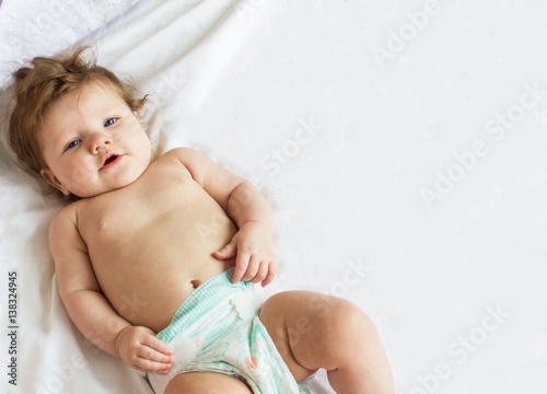 Funny beautiful little baby lying on a white diaper.