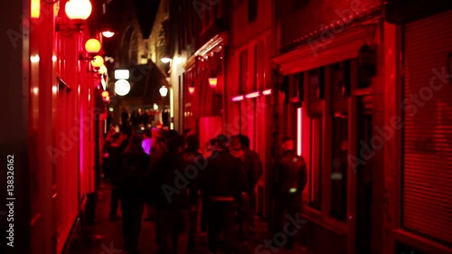 Groups of men stroll streets of red light district at night in Amsterdam
