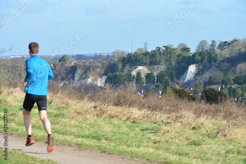Fototapeta Naklejka Na Ścianę i Meble -  A jogger running along a path by chalk hills in Coulsdon, Surrey.