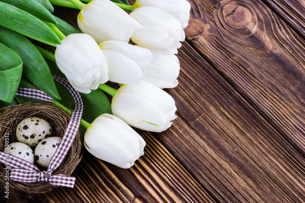 Naklejka premium Bouquet white tulip flowers with easter eggs on old wooden table. Place for text.
