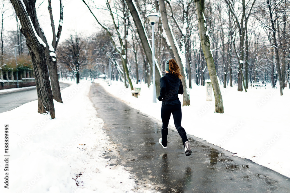 Female athlete jogging in park in winter Female athlete jogging in park in winter